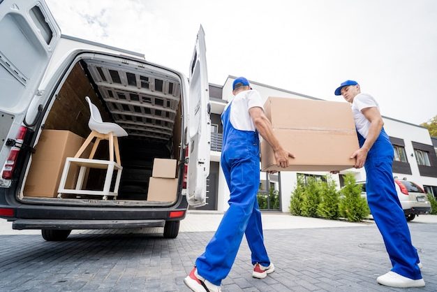 two-removal-company-workers-unloading-boxes-furniture-from-minibus_179755-13990